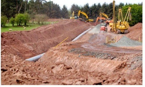 Pipeline construction trench with excavators and pipe sections